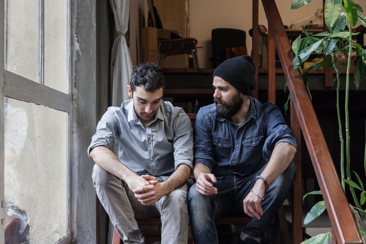 two men sitting on a staircase talking - sponsorship in alcoholics anonymous - summit bhc - addiction treatment centers and recovery