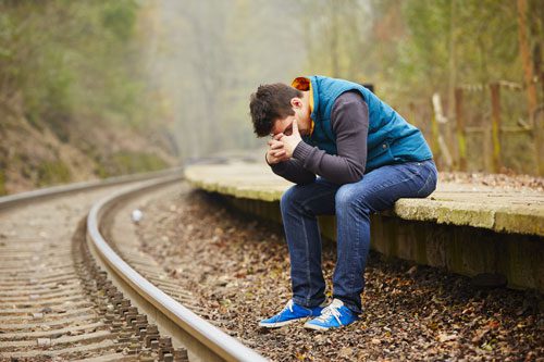 enabling behaviors and how they harm addiction recovery - sad man - train tracks - summit behavioral health
